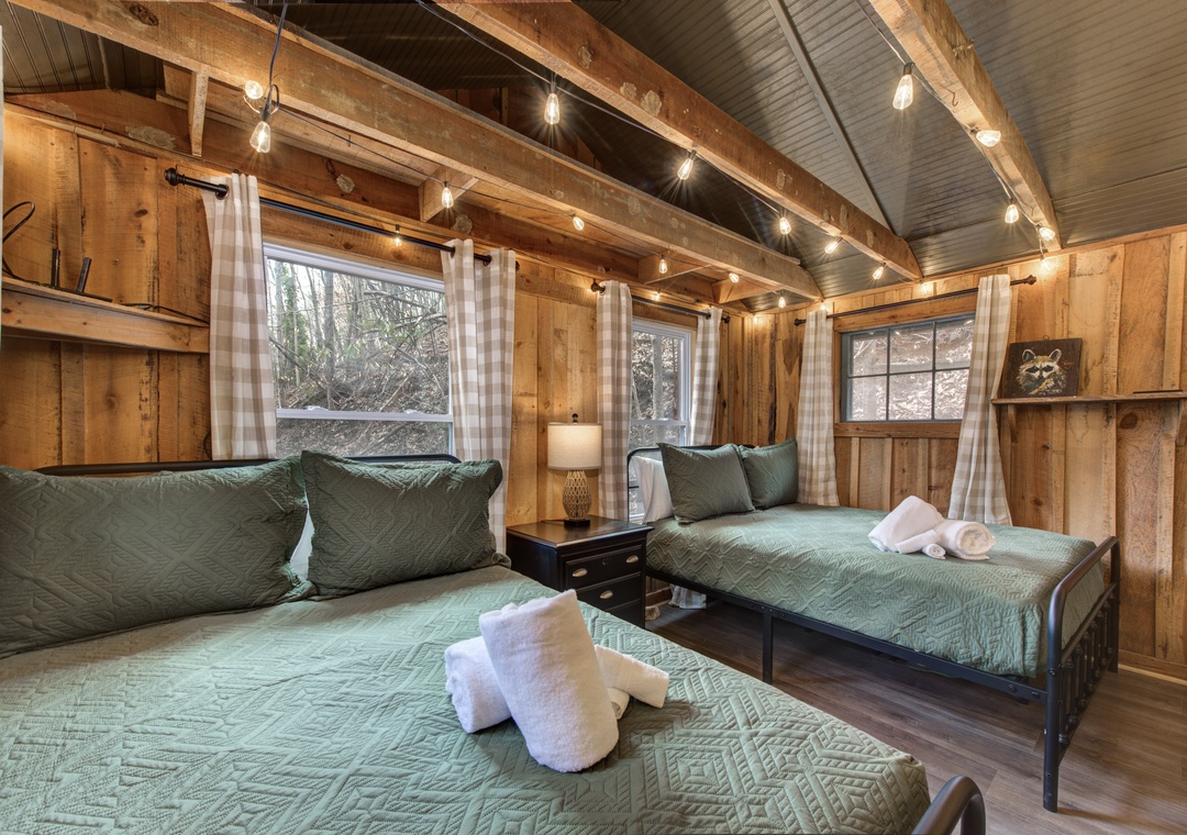 Your rustic bedroom features warm wood walls, string lights, and cozy twin beds perfect for a peaceful mountain retreat.