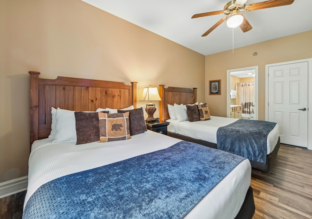 Sink into comfort with twin beds featuring rustic wood headboards and cozy blue accents in your peaceful retreat.