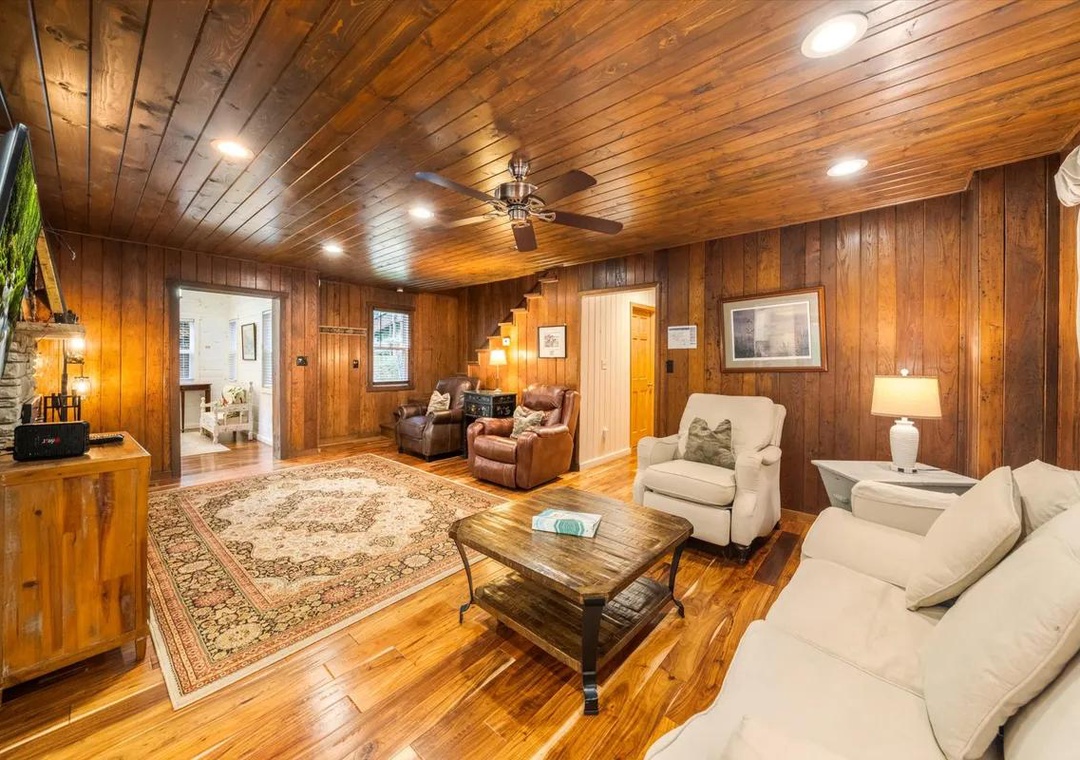 Sink into comfort in your spacious living room, where rich wood paneling and gleaming hardwood floors create a warm, cabin-like retreat perfect for cozy evenings together.