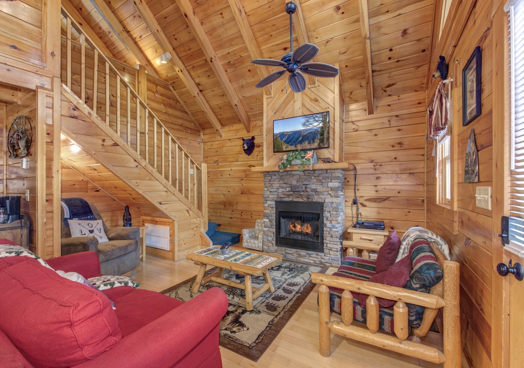 Cozy up in your rustic living room with warm wood walls, stone fireplace, and comfortable seating for relaxing mountain evenings.