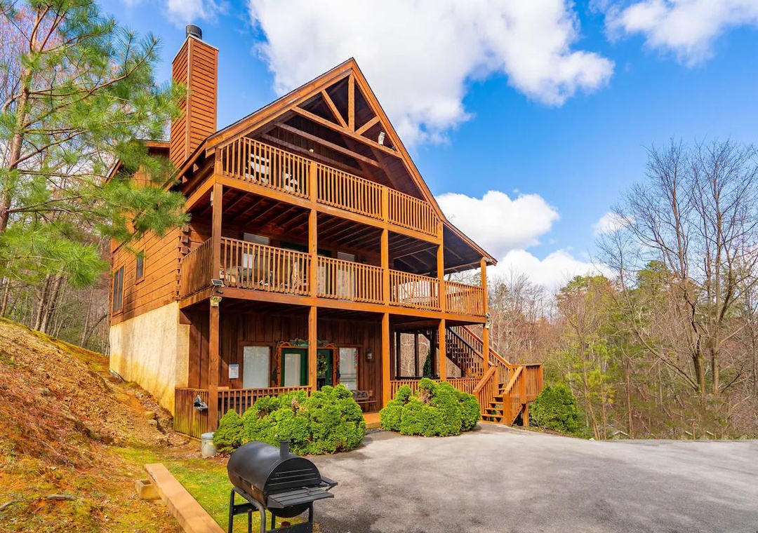Beautiful three-story log cabin nestled in wooded hillside with multiple decks and outdoor grilling area for mountain getaway.