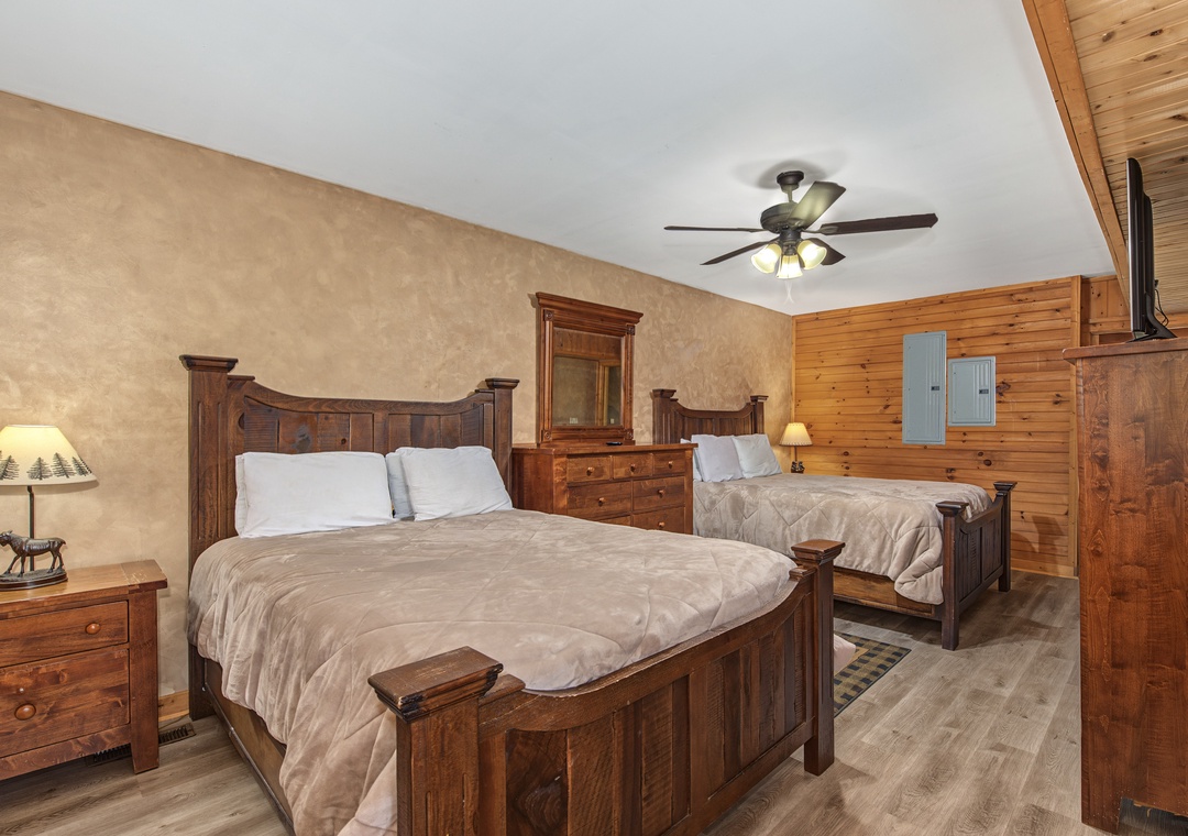Rustic wood furnishings and warm tones create a cozy mountain retreat where you can unwind after a day of adventure. Two comfortable beds promise restful sleep under the gentle glow of the ceiling fan.