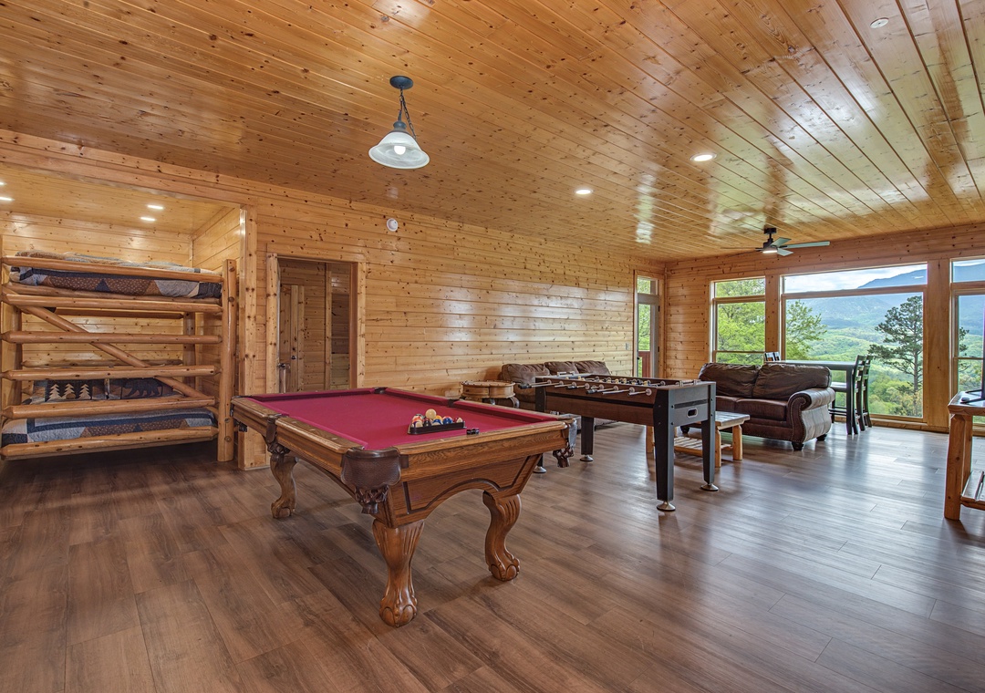 Your entertainment haven features a pool table, foosball, and bunk beds under soaring wood ceilings with stunning mountain views.