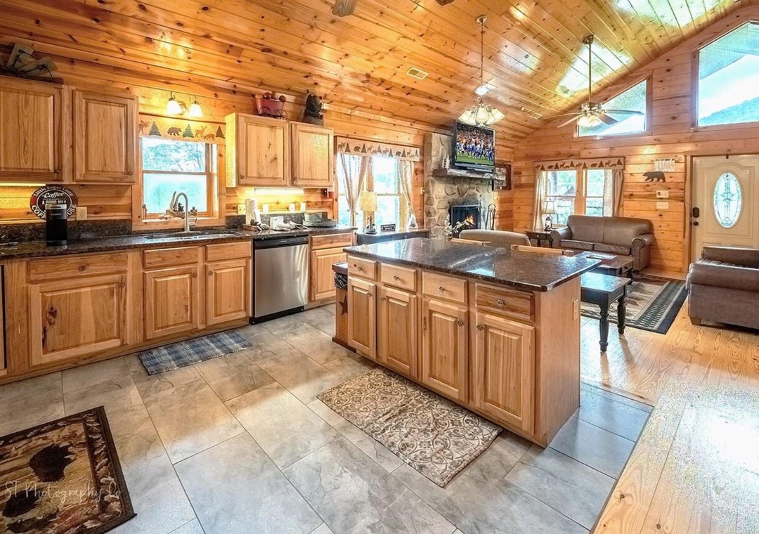 Gather with loved ones in this open-concept cabin featuring a fully-equipped chef's kitchen, cozy stone fireplace, and inviting living space with mountain views.