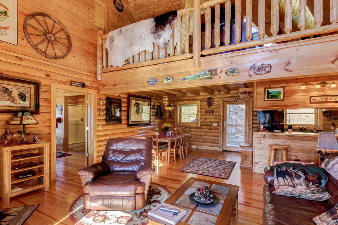 Step into your cozy log cabin retreat where warm wood surrounds you. Natural light fills the open living space, connecting kitchen, dining, and lofted bedroom—perfect for relaxing together after your mountain adventures.