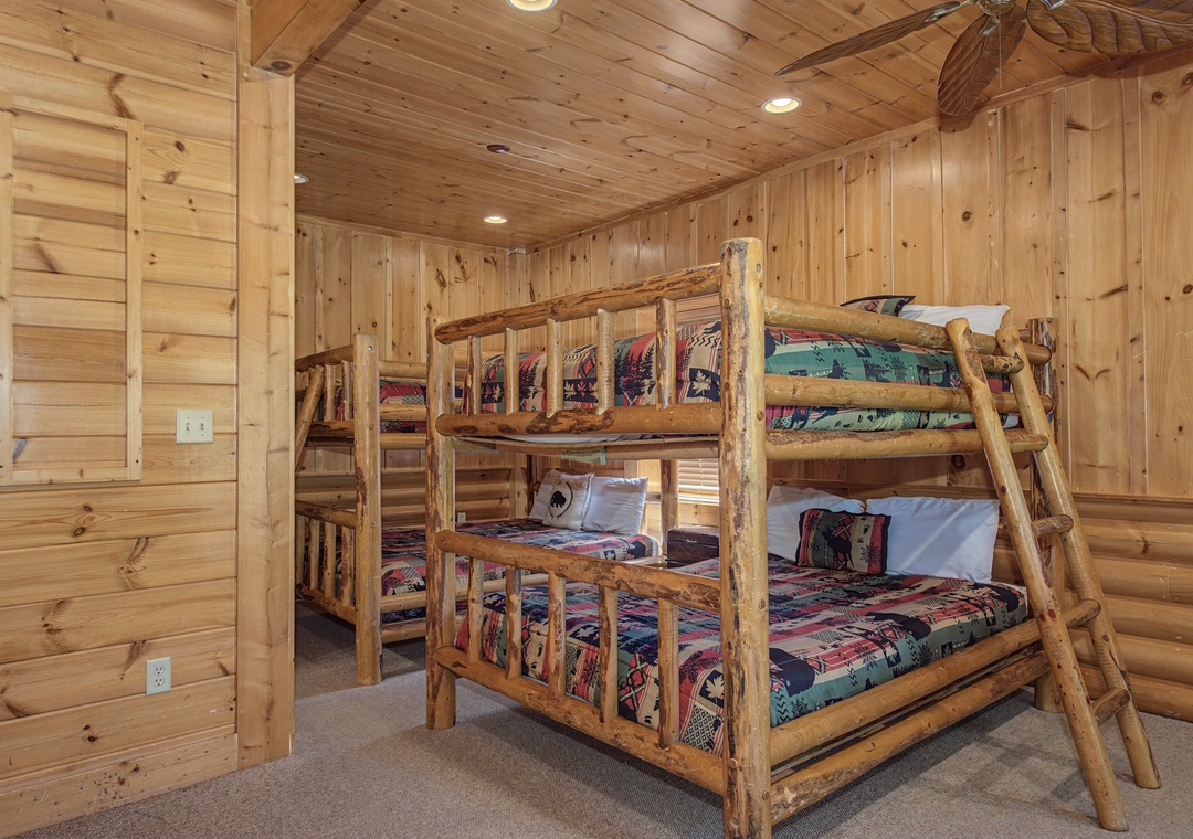 Sleep soundly in your cozy log cabin bedroom featuring handcrafted bunk beds with rustic charm and colorful mountain-themed bedding.