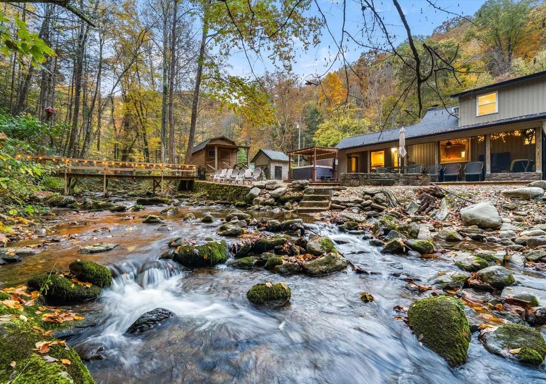 A secluded retreat nestled along a rushing mountain stream, surrounded by vibrant autumn foliage and natural beauty, with a charming footbridge connecting forested pathways to your riverside escape.