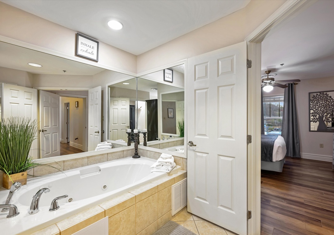 Indulge in your private spa-like retreat with a luxurious jetted tub surrounded by elegant tile and thoughtful touches like fresh towels.