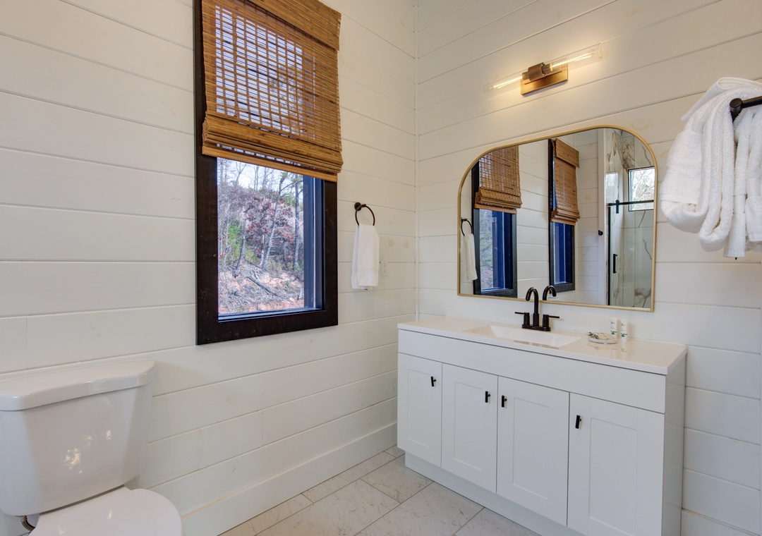 Your serene bathroom retreat features a soaking tub, elegant vanity, and warm natural light through bamboo shades.