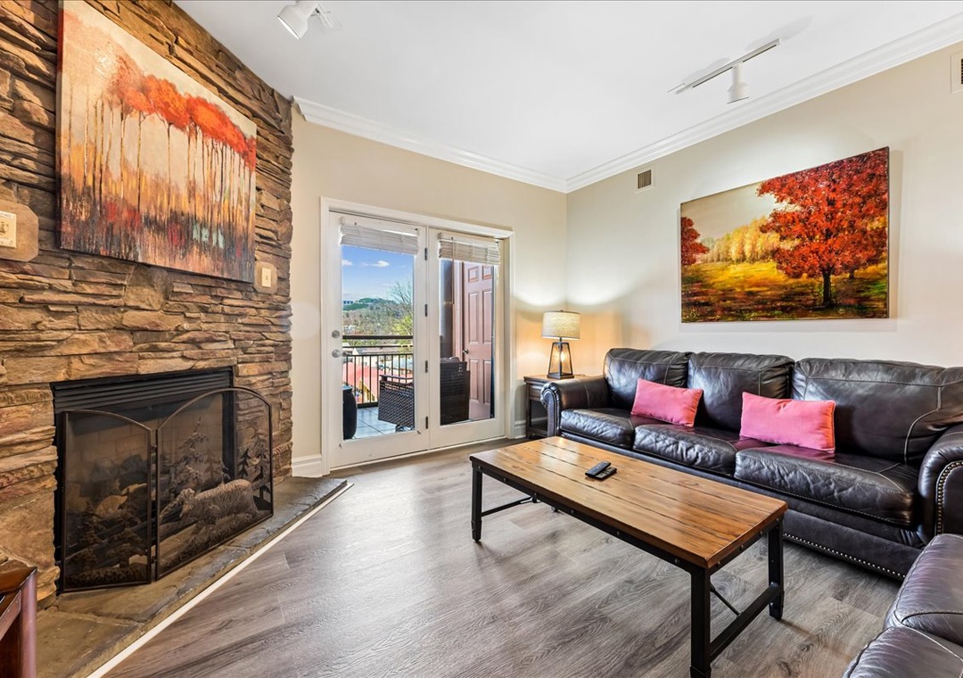 Sink into your plush leather sofa by the stone fireplace, where warm artwork and balcony views create the perfect retreat.