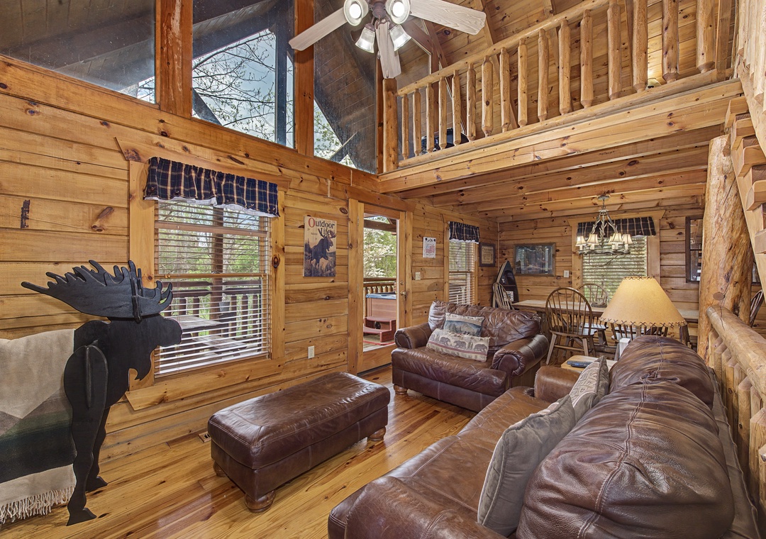 Unwind in your rustic cabin's living room where leather sofas invite cozy evenings beneath soaring wood ceilings and mountain charm.