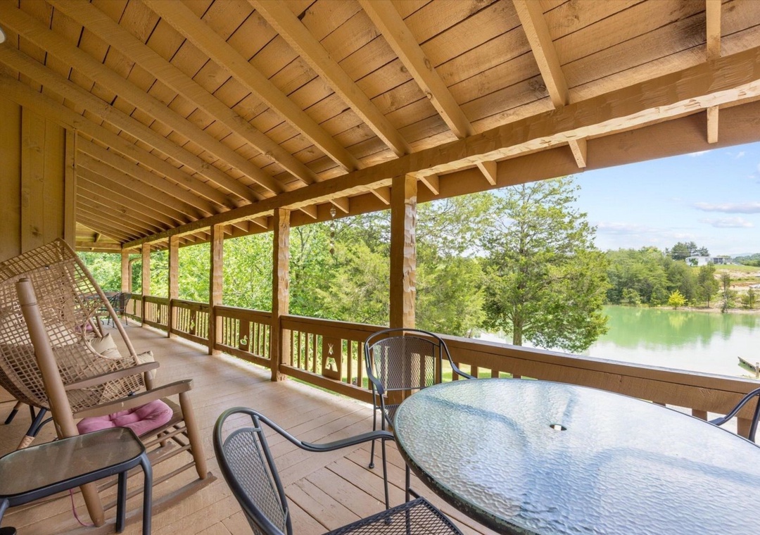 Unwind on your private lakefront deck with stunning water views and comfortable outdoor seating under rustic exposed beams.