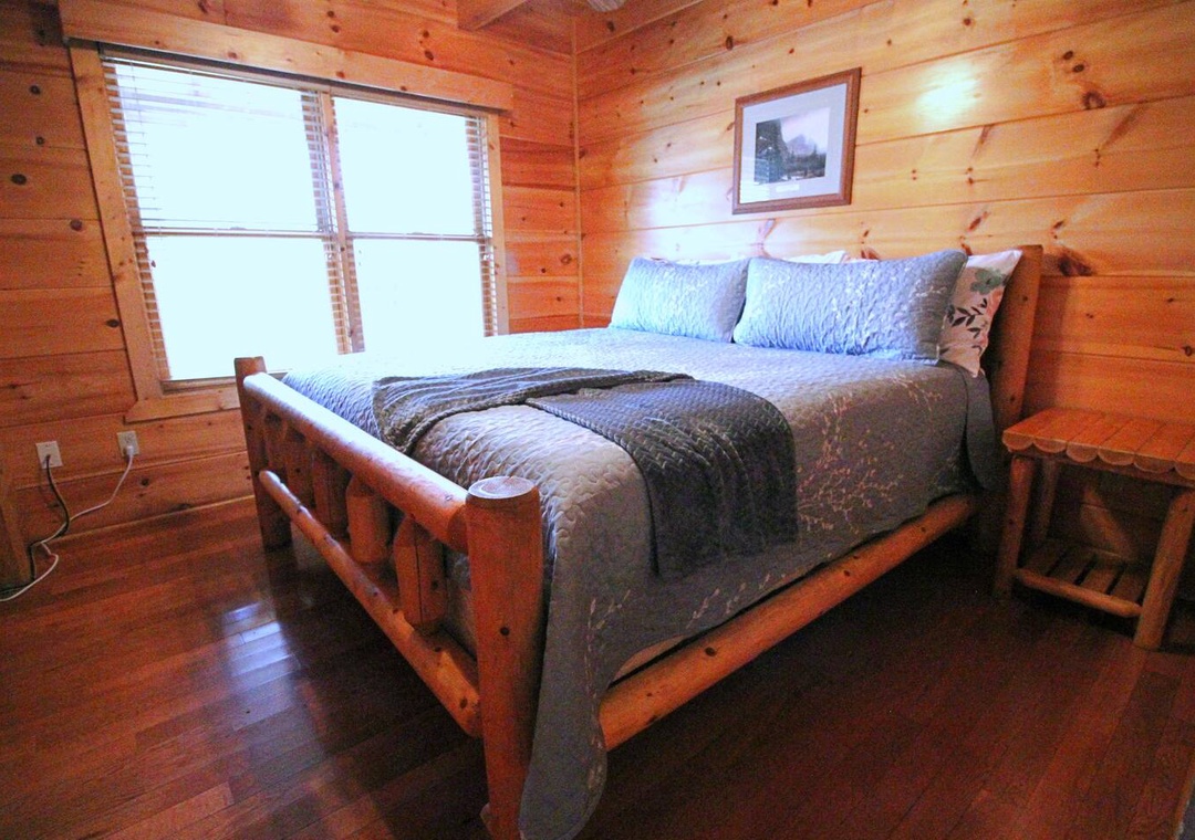 Your cozy log cabin bedroom features warm wood walls and a rustic handcrafted bed for peaceful mountain nights.
