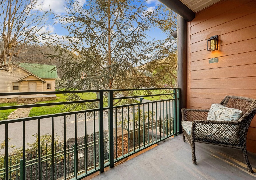 Your private balcony invites peaceful mornings with wicker seating overlooking green spaces and neighborhood charm.