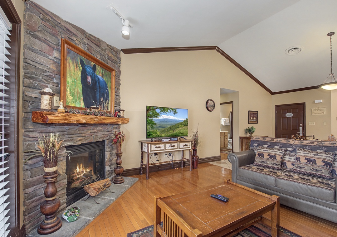Cozy up by the crackling stone fireplace while enjoying mountain views on the flatscreen TV in this rustic living space.