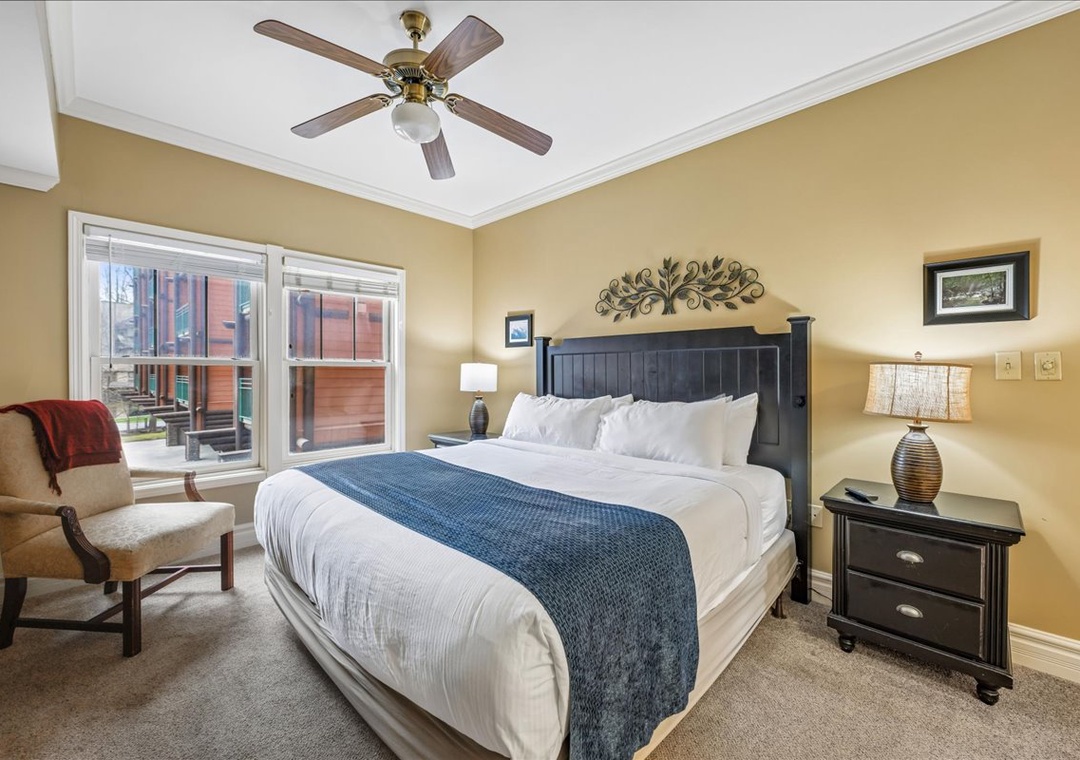 Drift off in this welcoming bedroom featuring crisp linens, gentle ceiling fan breezes, and views of the surrounding area.