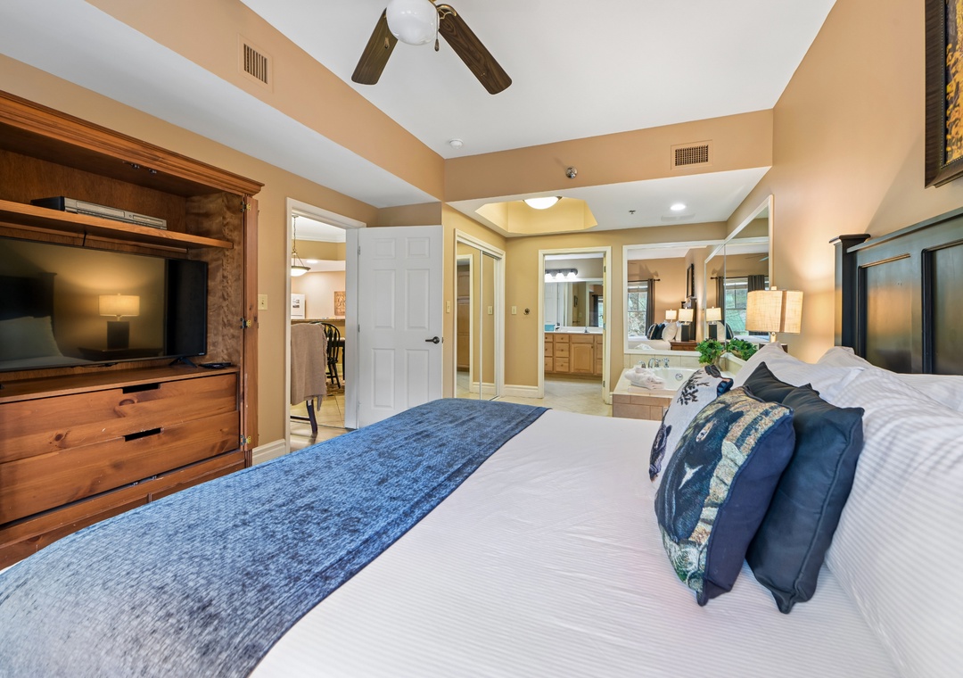 Unwind in your spacious master suite with plush bedding, warm wood accents, and a cozy entertainment center for relaxing evenings.