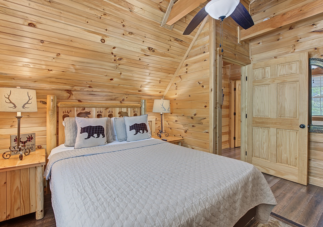 Sink into this rustic bedroom with cozy wood paneling, a handcrafted bear-carved headboard, and plush linens that invite you to unwind completely.