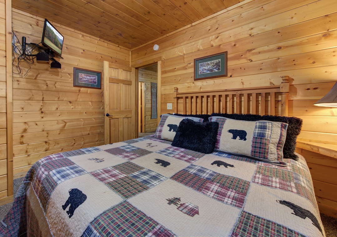 Drift off to sleep in your cozy cabin bedroom, surrounded by warm wood walls and charming bear-themed bedding that makes you feel at home.