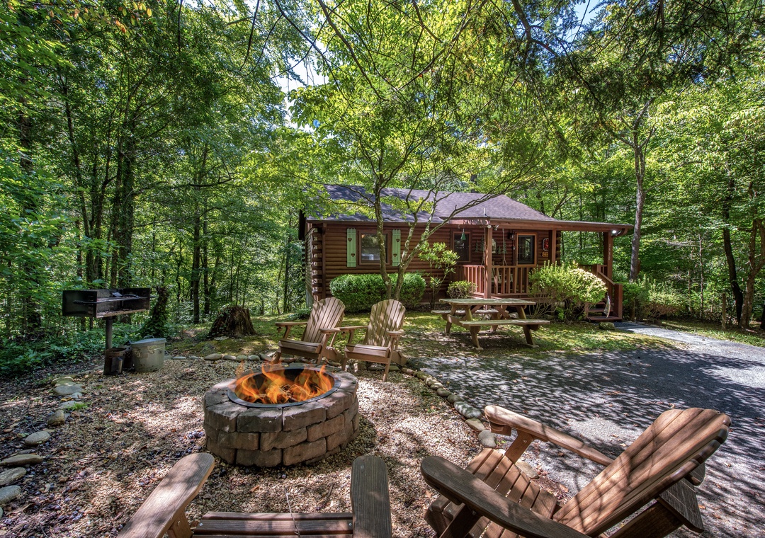 A private wooded retreat nestled among towering trees, featuring a cozy fire pit with Adirondack chairs and a covered porch perfect for peaceful forest evenings.