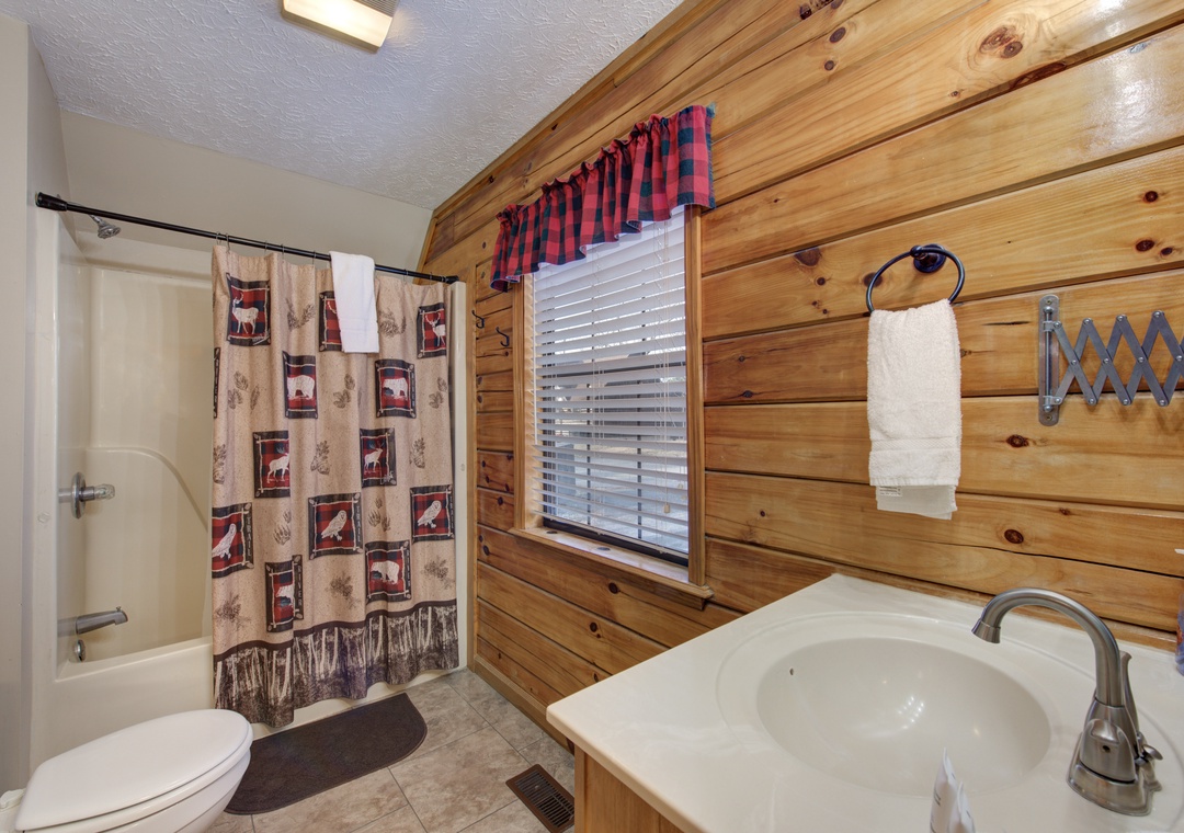 Your cozy cabin bathroom features warm wood walls and rustic charm, with fresh towels and thoughtful touches ready for you.