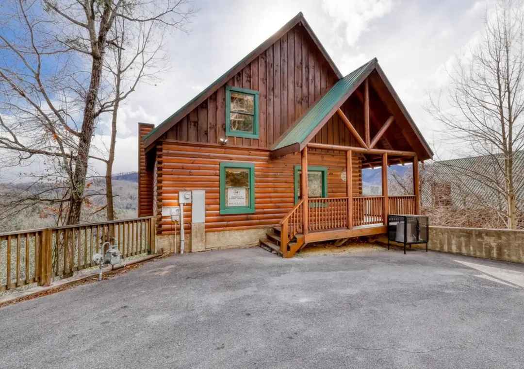 A charming log cabin with a welcoming front porch and convenient parking, nestled among the trees with stunning mountain vistas in every direction.