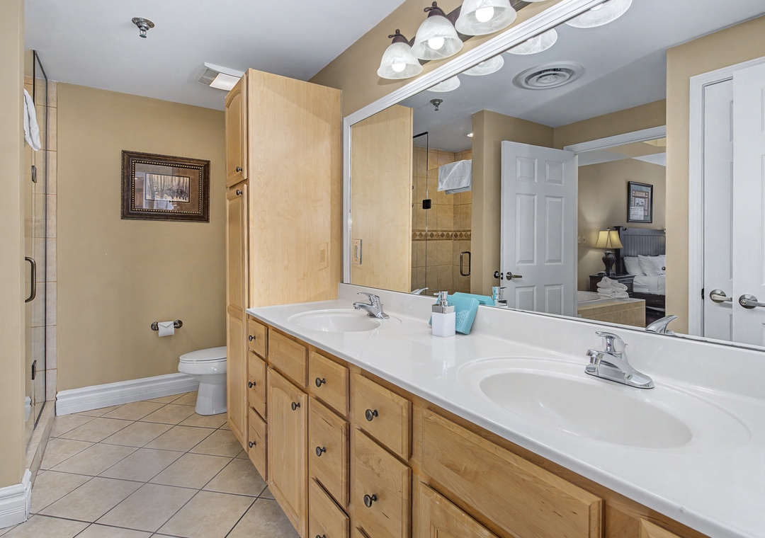Your spacious master bathroom features dual sinks and warm wood cabinetry, perfect for morning routines together.