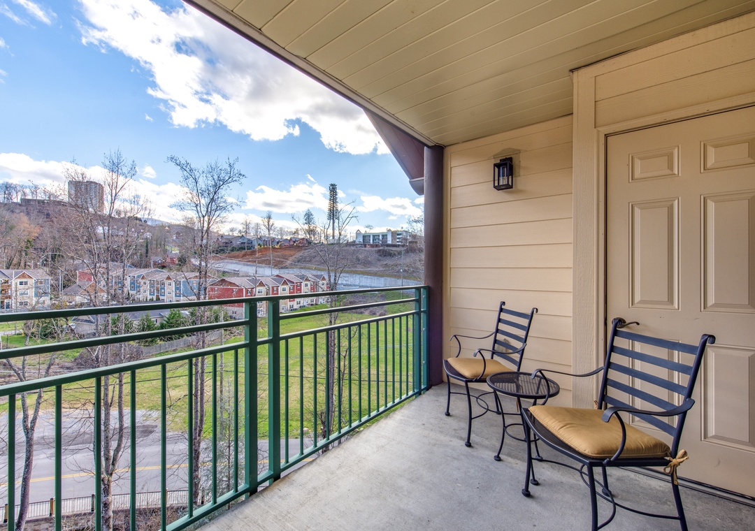Covered balcony with seating overlooking a scenic cityscape and parkland area.