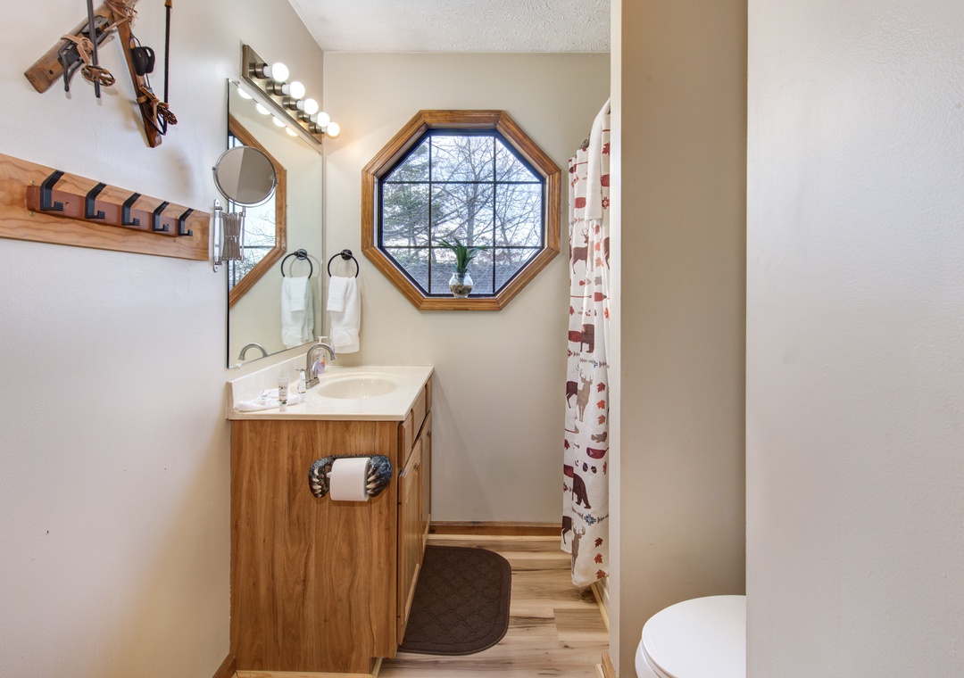 Your charming bathroom features warm wood touches and a unique octagonal window that frames peaceful tree views as you refresh.