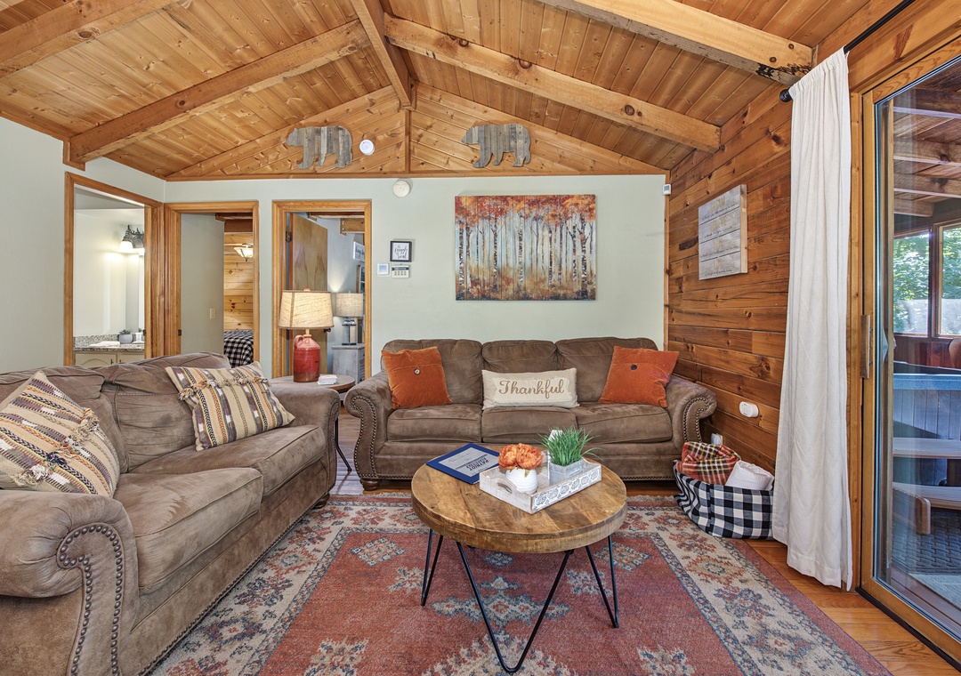 Sink into plush seating under soaring wood-beamed ceilings as natural light fills your inviting living room, perfect for unwinding after a day of adventure.