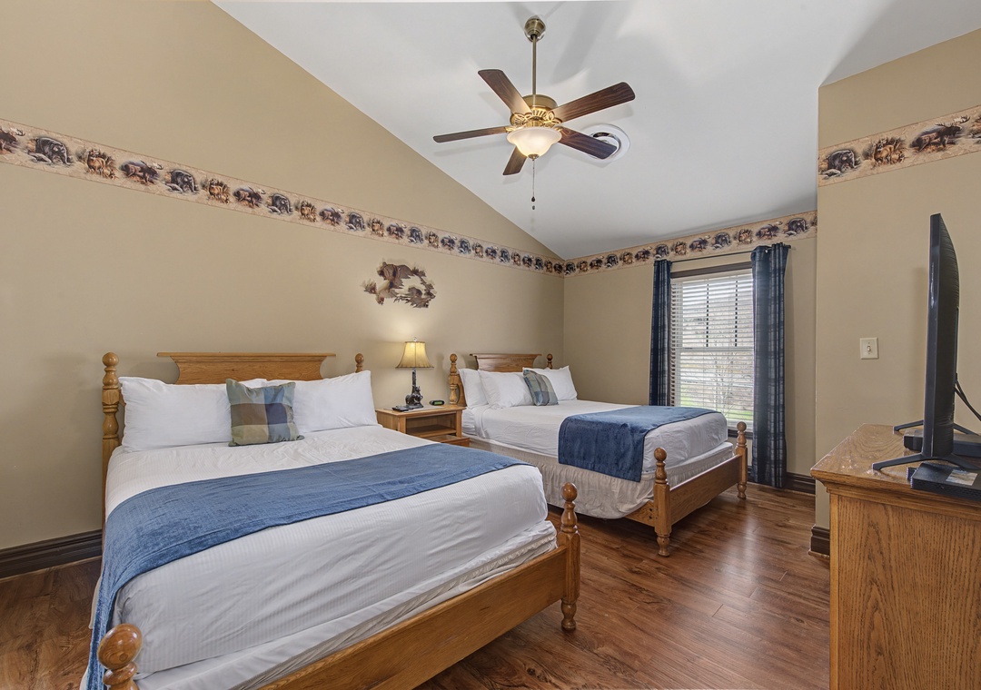 Rest in comfort with two cozy beds featuring crisp linens and rustic charm, complete with warm wood floors and gentle ceiling fan.
