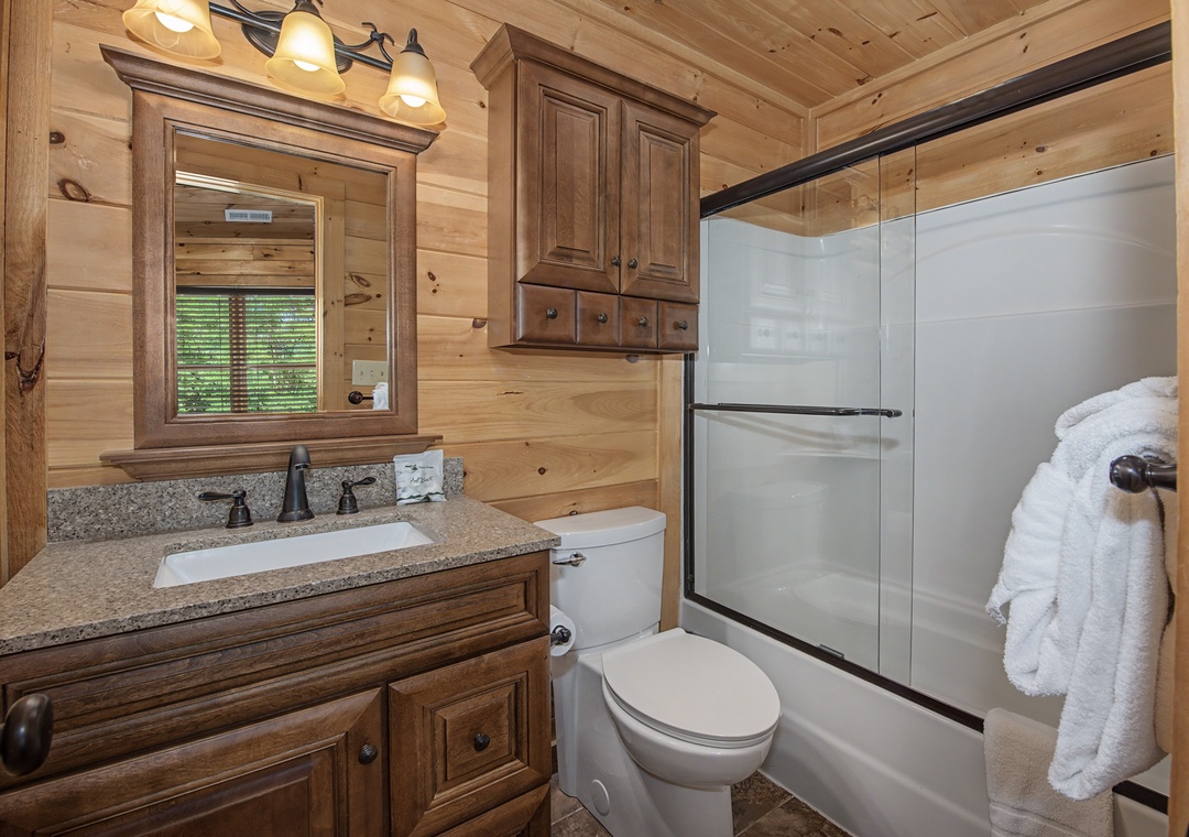 Your private bathroom features a granite vanity, full shower-tub combo, and plush towels. Rustic wood finishes and warm lighting create a cozy, cabin-style retreat perfect for unwinding.