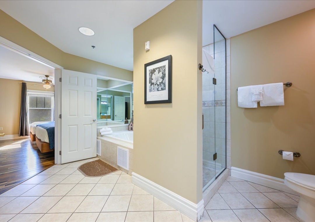 Your spacious bathroom suite features a glass-enclosed shower, soaking tub, and fresh towels for your comfort.