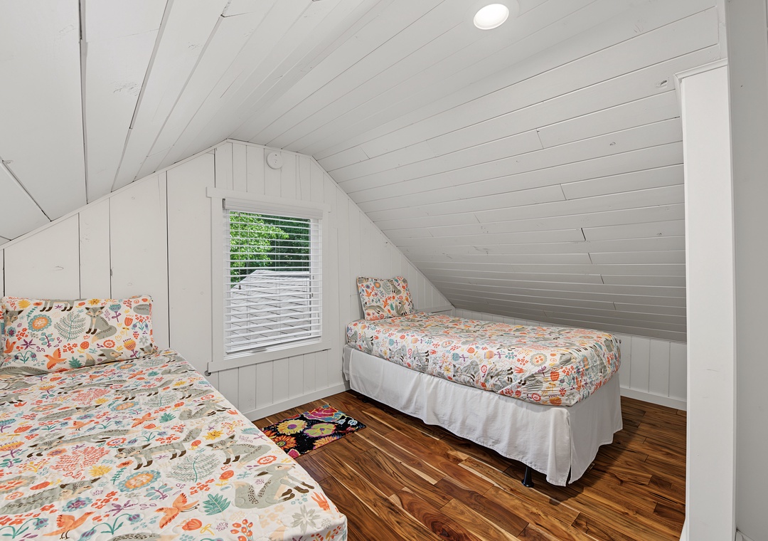 Cozy under the eaves, your sleeping space offers cheerful linens, warm wood floors, and natural light that makes mornings feel bright and inviting.