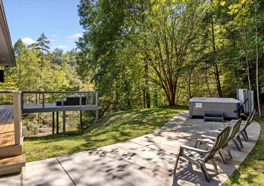 Your private backyard oasis features a spacious patio with comfortable seating and hot tub, surrounded by lush trees for ultimate relaxation.