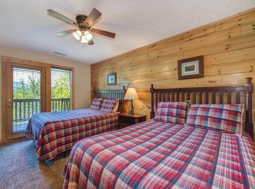 Drift off in cozy comfort surrounded by warm wood walls and plaid bedding, with forest views greeting you each morning.