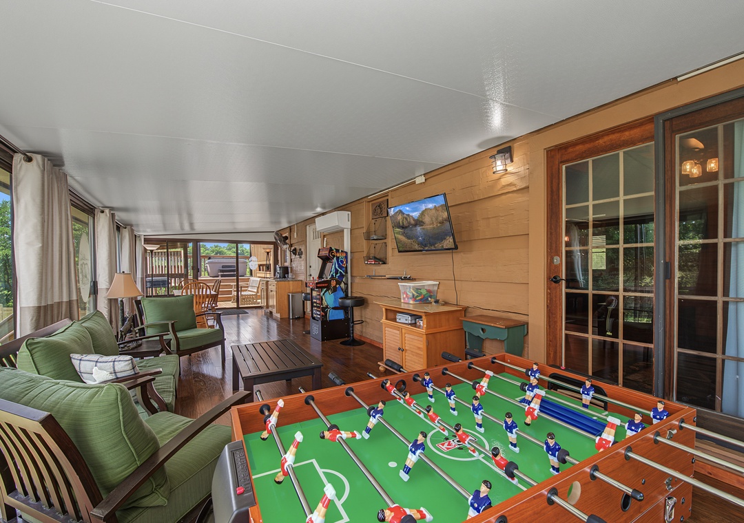 Gather round the foosball table for friendly competition, relax on plush green sofas, and enjoy your favorite shows in this inviting covered porch space.
