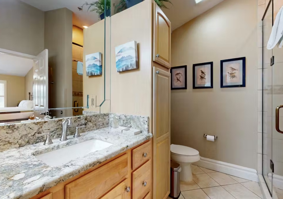 Your spacious bathroom features elegant granite countertops, warm wood vanity, and a glass-enclosed shower for your comfort.