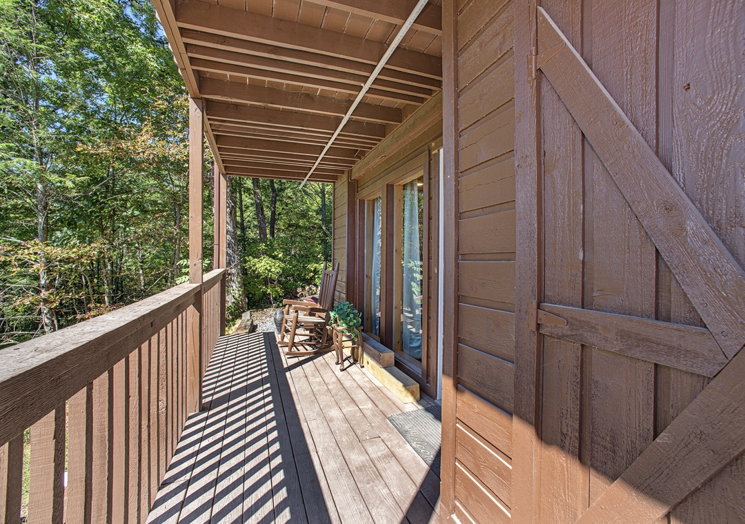 Your private covered balcony offers a peaceful retreat with rustic wooden seating and lush forest views all around.