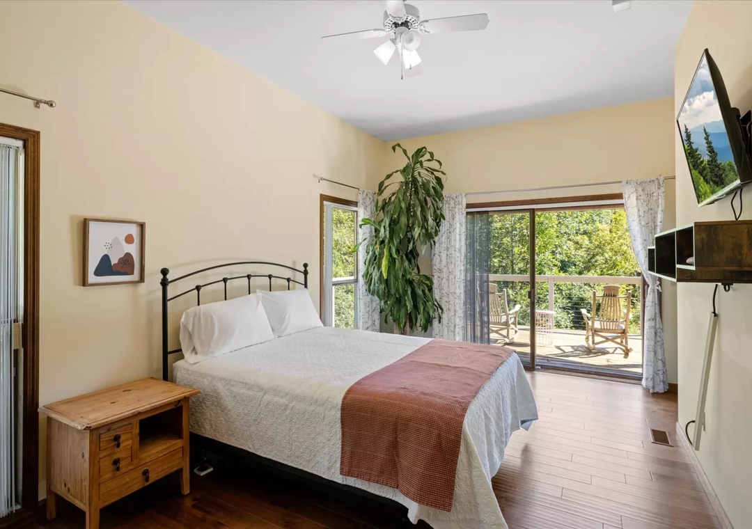 Your peaceful bedroom overlooks lush greenery through sliding doors that open to your private balcony, with cozy furnishings and modern amenities.