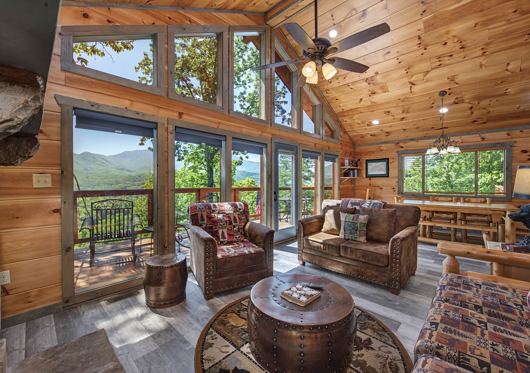 Relax in your sunlit living room with soaring ceilings and floor-to-ceiling windows framing breathtaking mountain views. Cozy leather seating invites you to unwind and savor the scenery from your private deck.