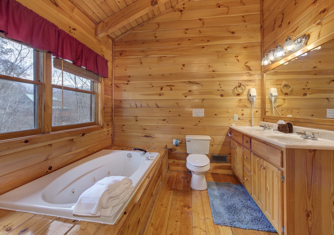 Soak your worries away in this rustic cabin bathroom's jetted tub while natural light streams through the window.