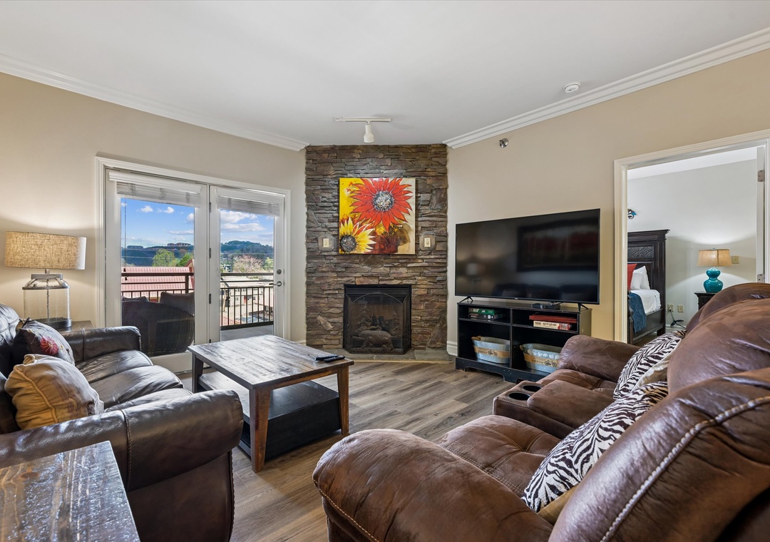 Relax in your spacious living room with cozy leather seating, stone fireplace, and mountain views from your private balcony.
