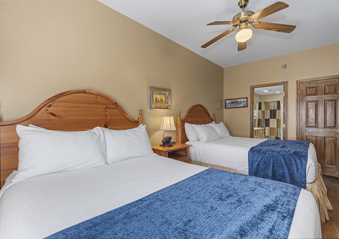 Unwind in your spacious bedroom with two plush beds, warm wood furnishings, and a gentle ceiling fan keeping you comfortable all night.