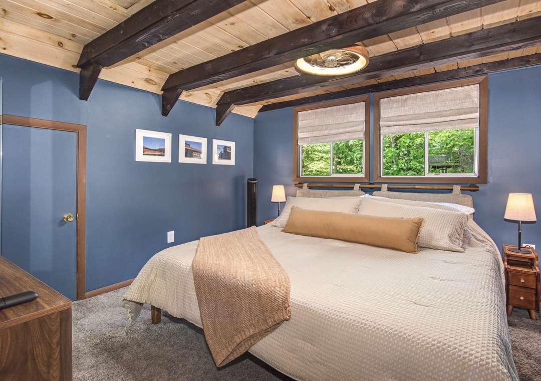 Your peaceful retreat features a plush king bed under rustic exposed beams, where soft linens and warm lighting create the perfect sanctuary for restful nights after exploring.