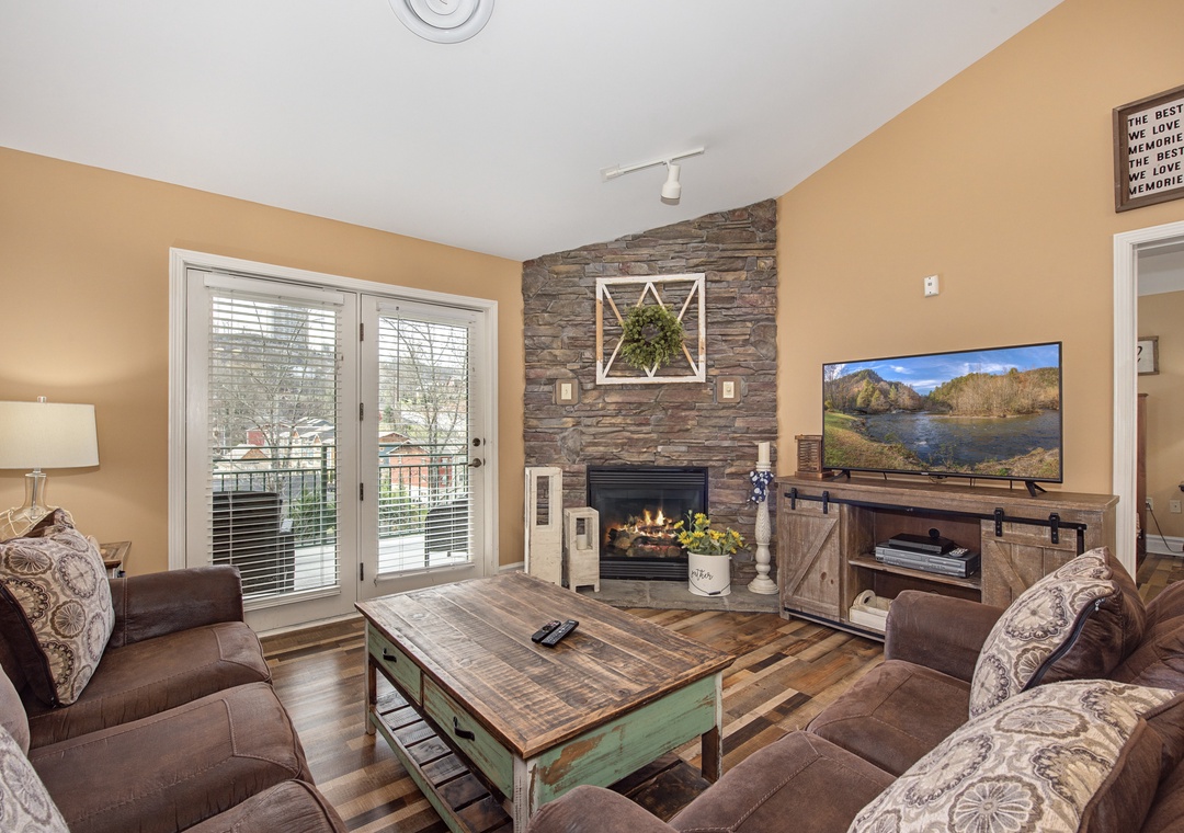 Cozy up in your rustic living room with stone fireplace, plush seating, and entertainment center for perfect evening relaxation.