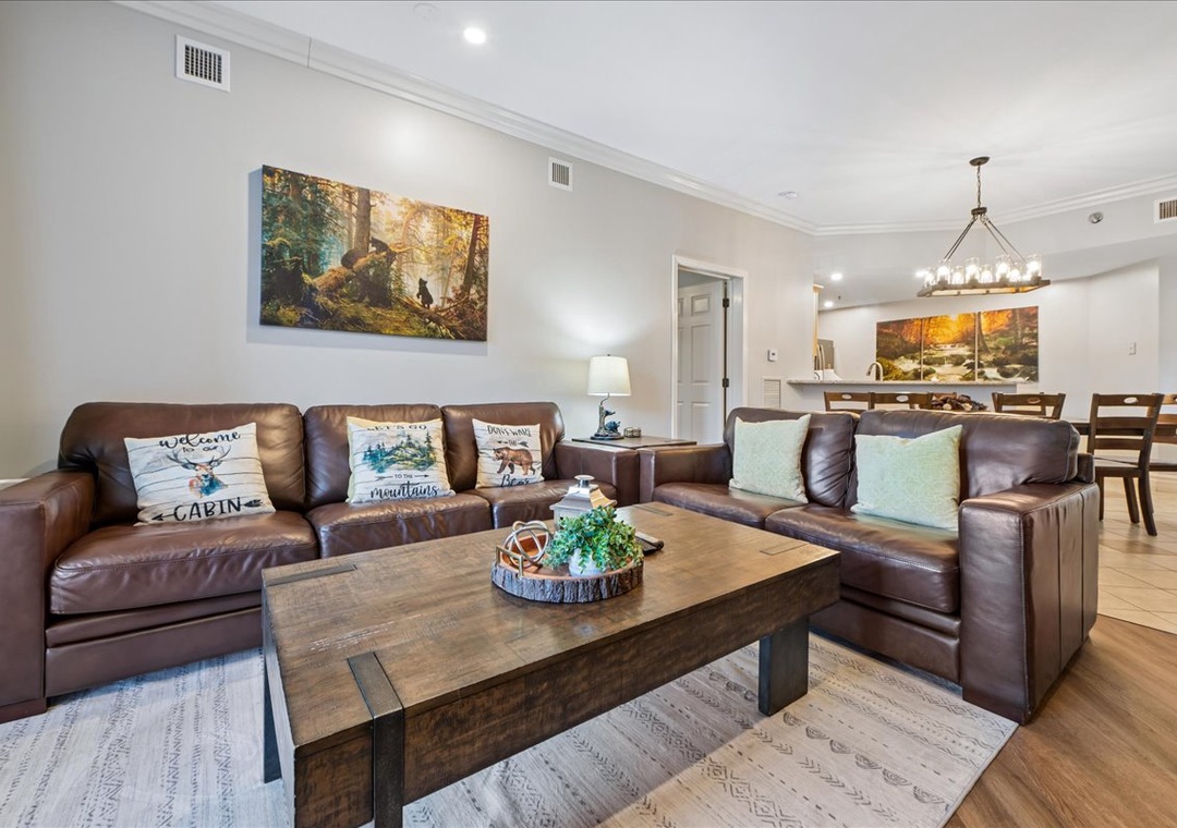 Sink into plush leather sofas in your spacious living area, where rustic mountain artwork and warm wood accents create the perfect retreat.