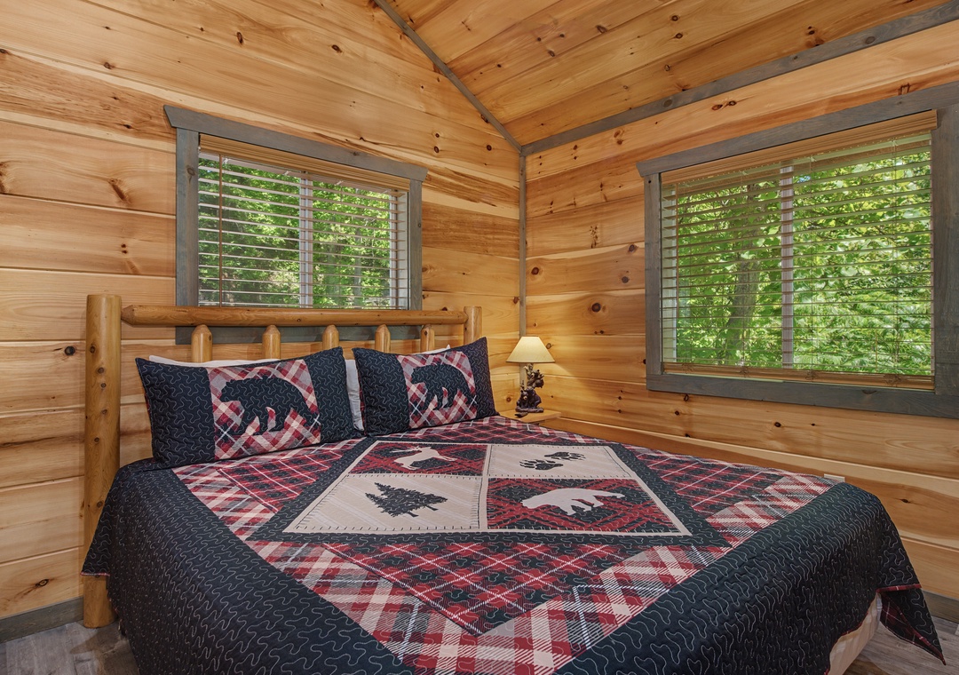 Drift off under vaulted wood ceilings in your cozy bedroom, where natural light filters through shuttered windows overlooking lush greenery.