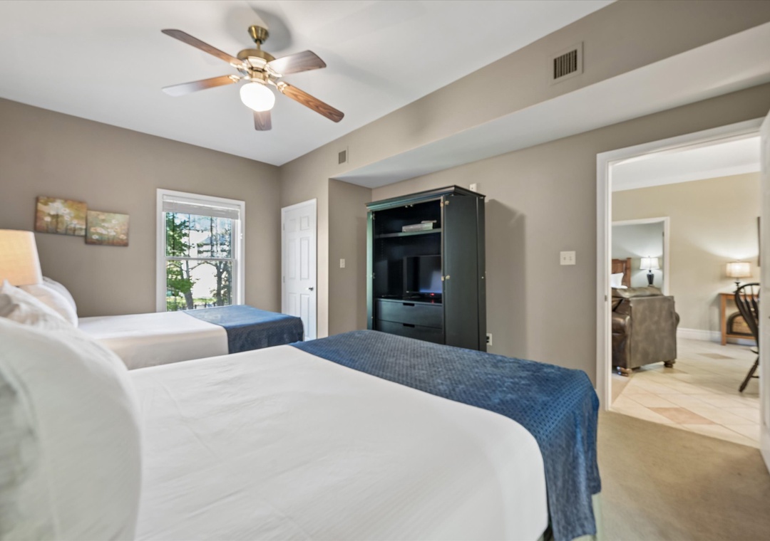 Relax in your spacious bedroom with two comfortable beds, ceiling fan, and entertainment center for cozy evenings in.