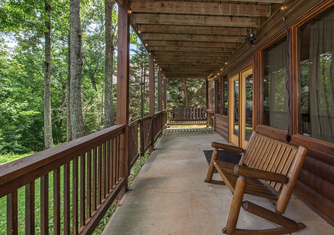 Step onto your private wraparound deck, where a cozy rocking chair awaits you beneath string lights. Surrounded by lush forest views, this peaceful outdoor space invites you to unwind in nature's embrace.